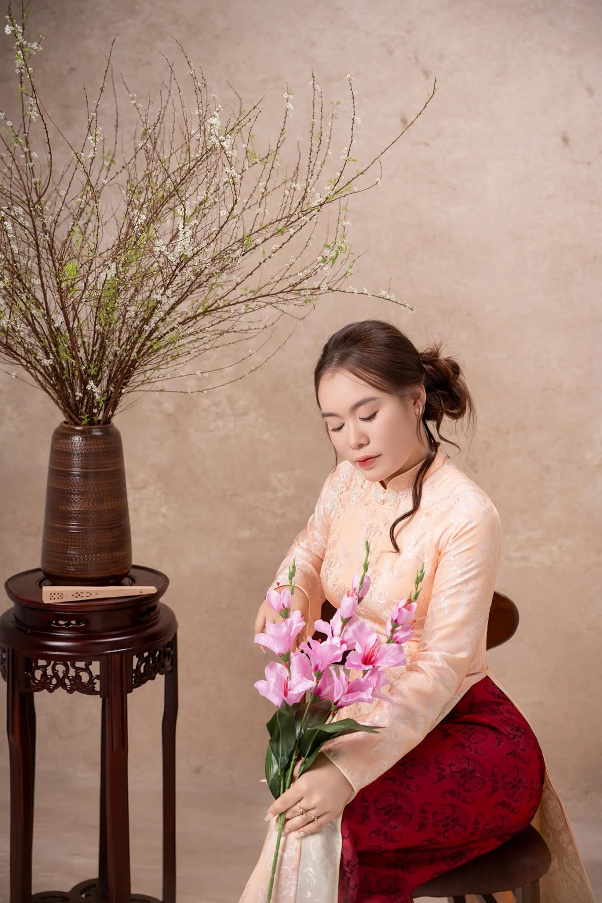 Cận cảnh cô gái áo dài cam cúi nhìn bó hoa lay ơn hồng trên tay