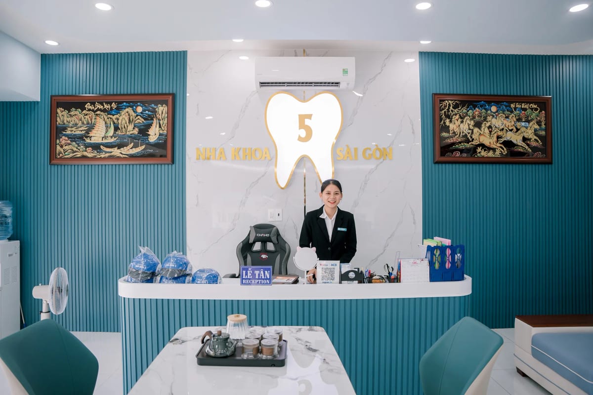 Quầy lễ tân phòng khám nha khoa với logo thương hiệu trên tường